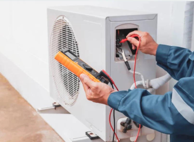 Technician testing an outdoor air-conditioning unit with a digital multimeter