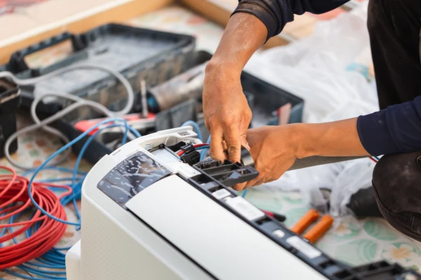 Hands repairing the internal components of a split air-conditioning unit