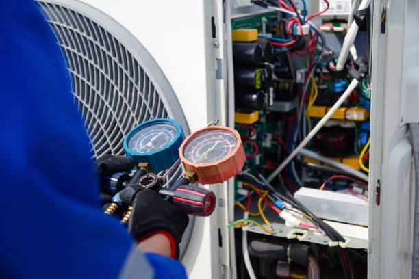 Technician checking HVAC equipment with refrigerant pressure gauges