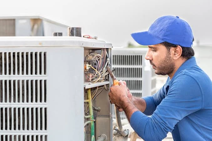 Technician inspecting the wiring of an outdoor HVAC condenser